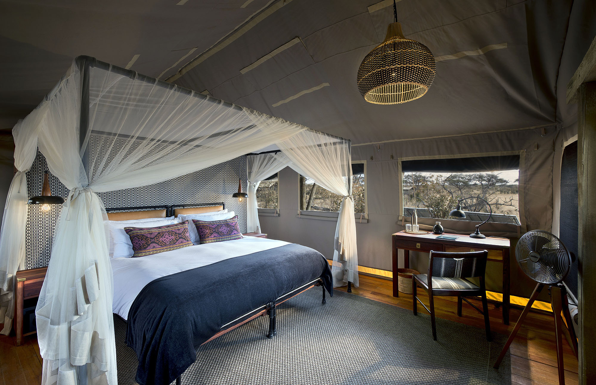 Elegantes Safarizelt mit Himmelbett, Moskitonetz und stilvoller Einrichtung in einer exklusiven Safari-Lodge in Afrika.